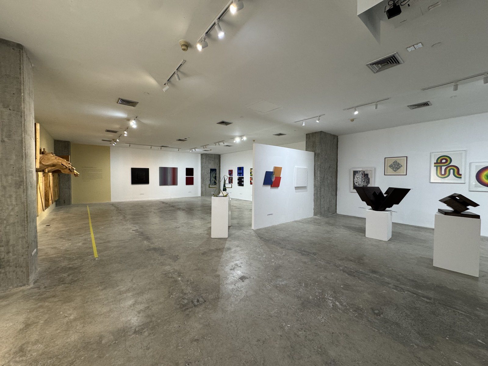 Sala principal de SAGA con pinturas y esculturas geométricas sobre pedestales blancos